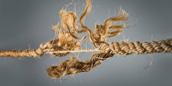 Frayed rope near to break on gray background. Selective focus
